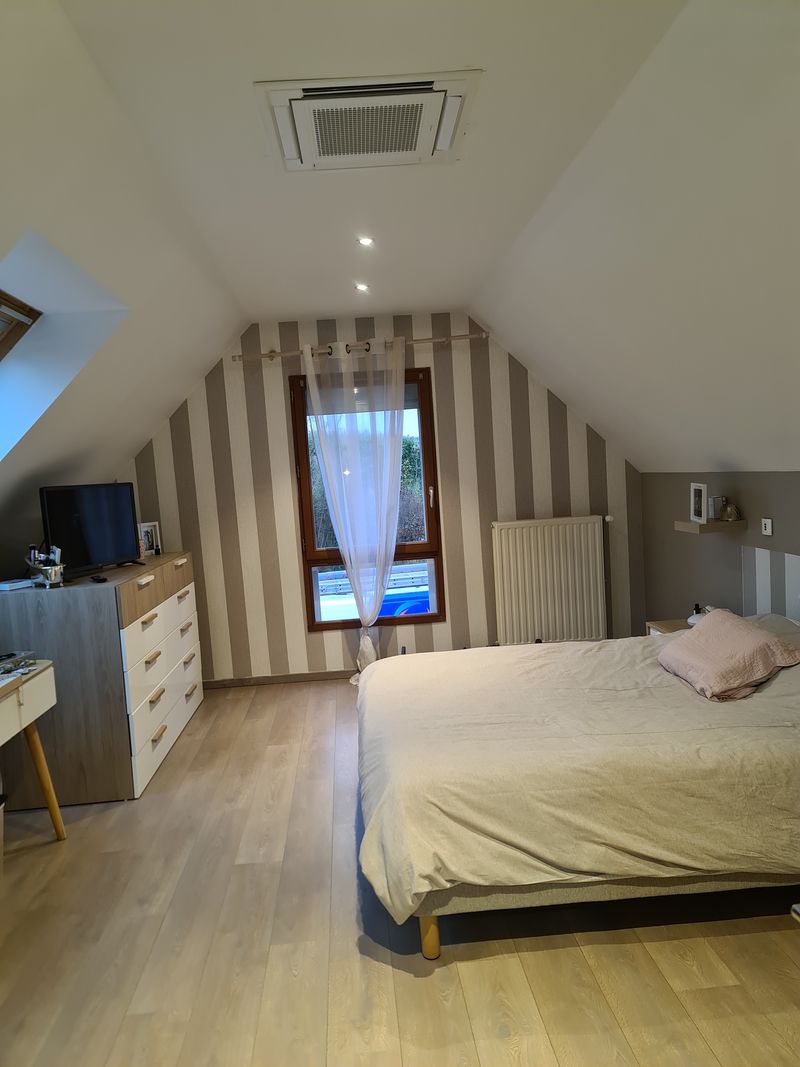 Climatiseur de type cassette encastré dans le plafond d’une chambre mansardée