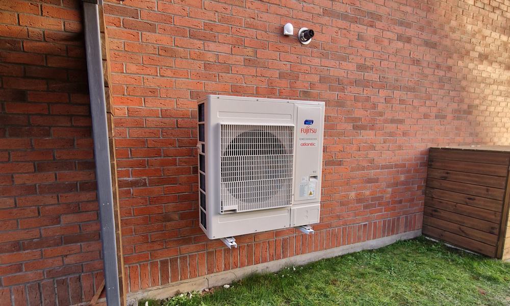 Unité extérieure de pompe à chaleur air-eau fixée sur un mur en briques