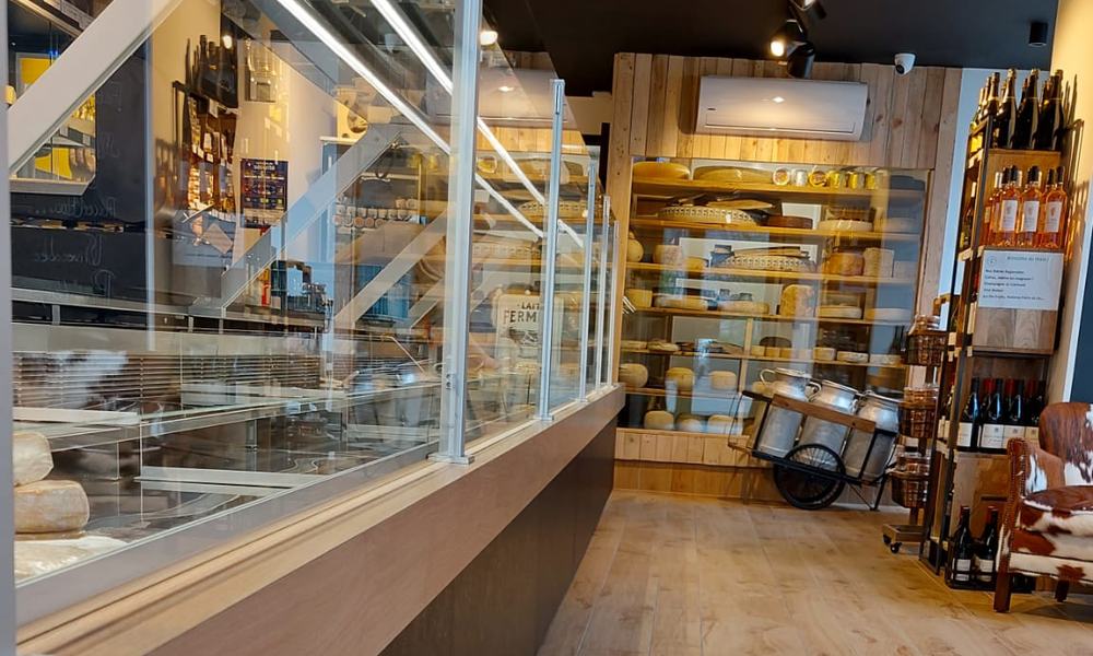 Climatiseur mural au fond d’une fromagerie, au-dessus de la vitrine à fromages